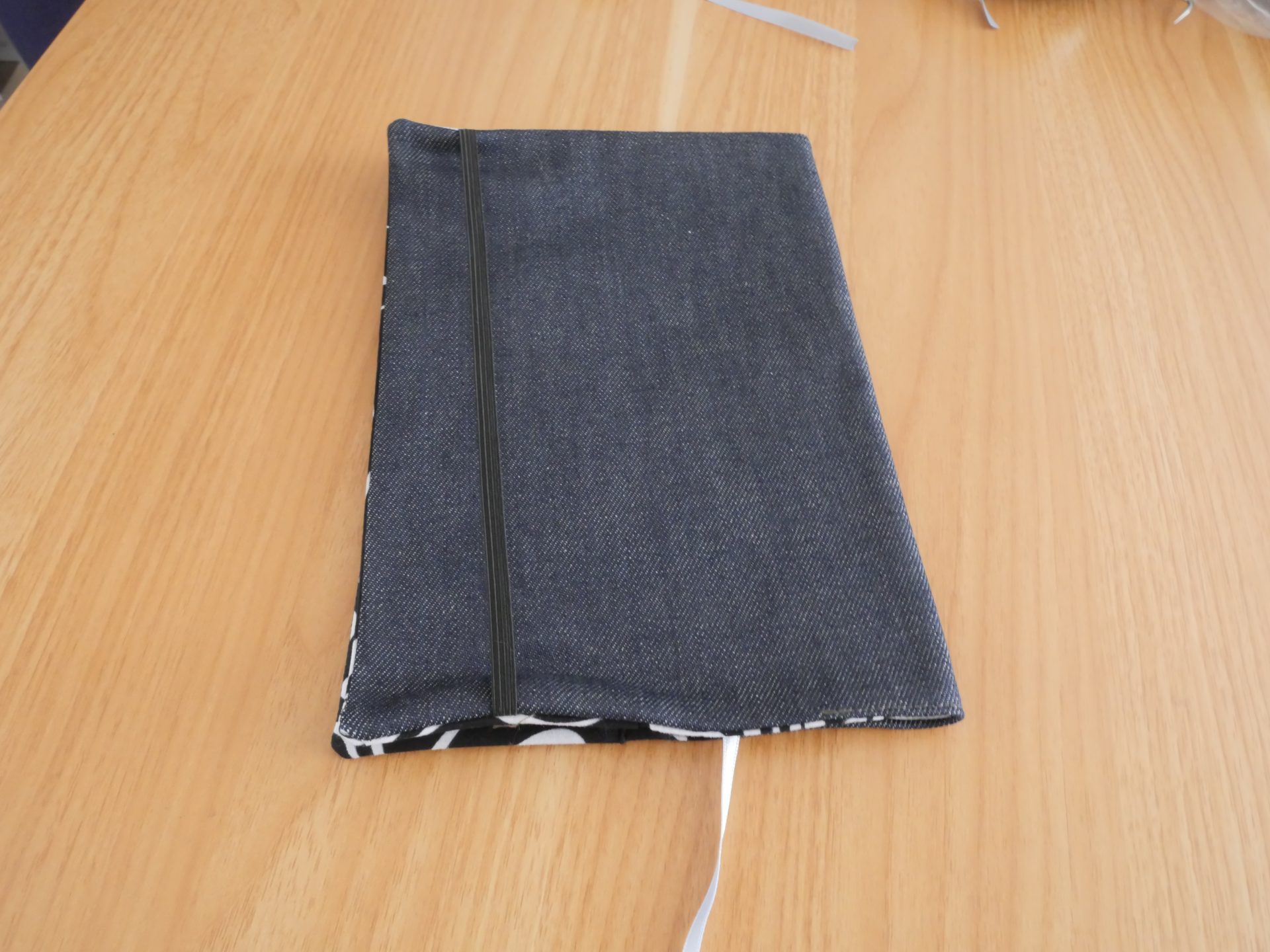 Dos du couvre-livre ratonetpanda ouvert, doublure tissu noir et blanc tourbillonnant avec poche et étiquette créateur