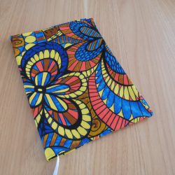Couvre-livre fait main en tissu wax africain coloré, ouvert, avec doublure jean gris, marque-page satin blanc et poche intérieure