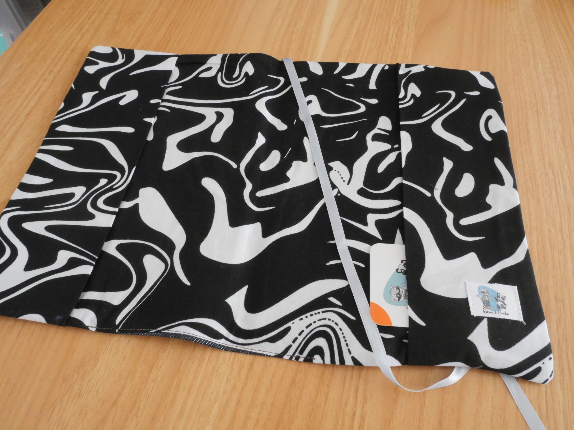 Intérieur du couvre-livre ratonetpanda ouvert, doublure tissu noir et blanc tourbillonnant avec poche et étiquette créateur