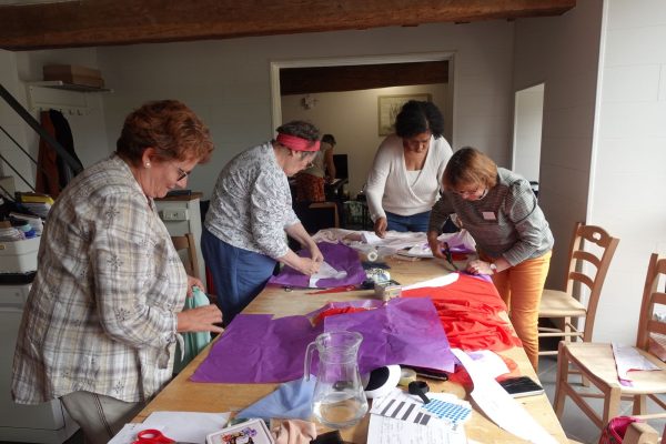 Participantes découpant leurs patrons en groupe sur la grande table de l'atelier