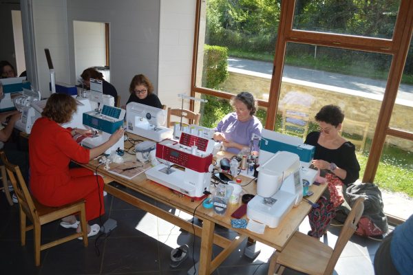 Salle de couture avec machines à coudre et grande baie vitrée pendant un stage